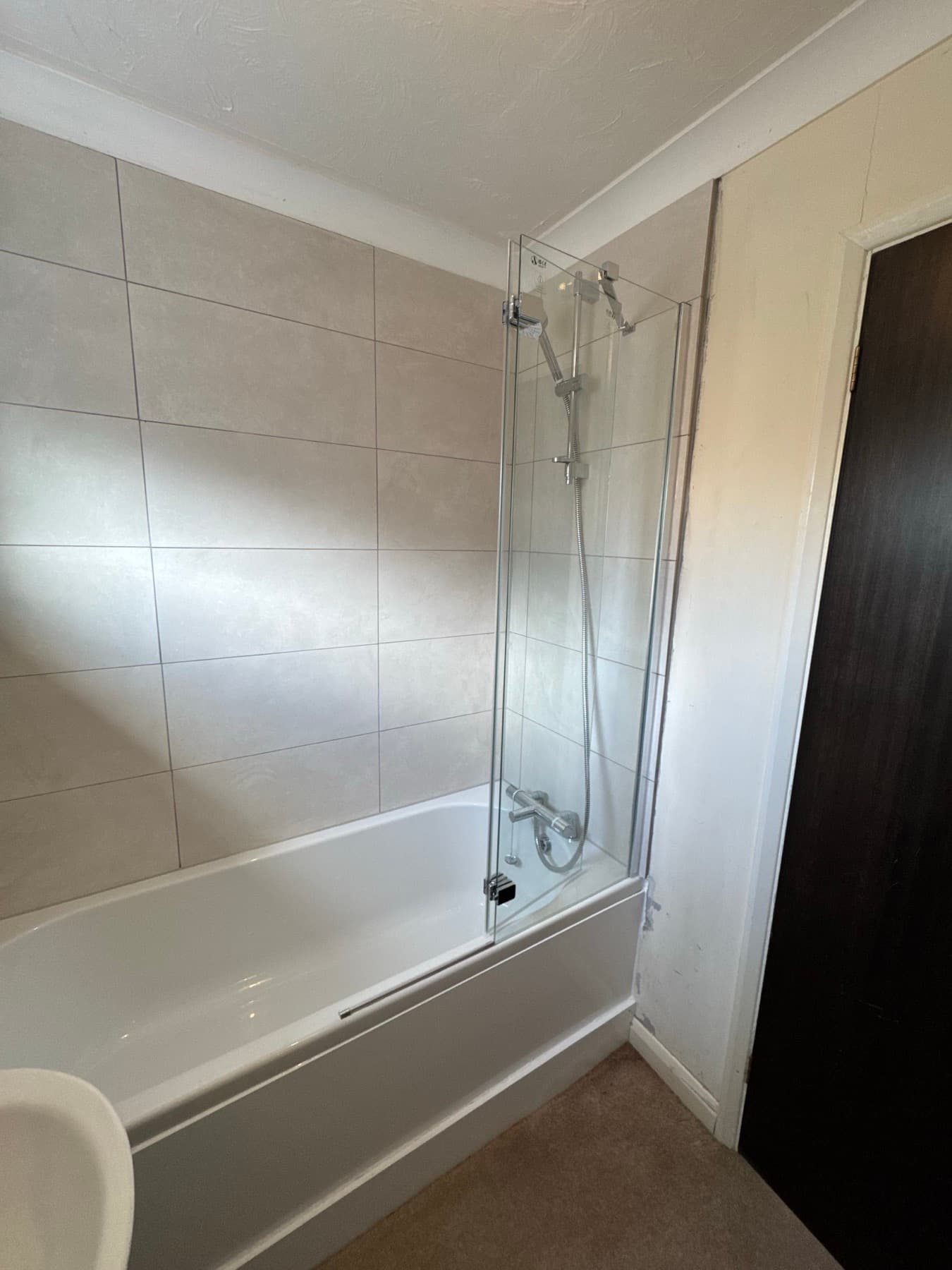 Bath with a hinged glass screen and a thermostatic bar shower over it