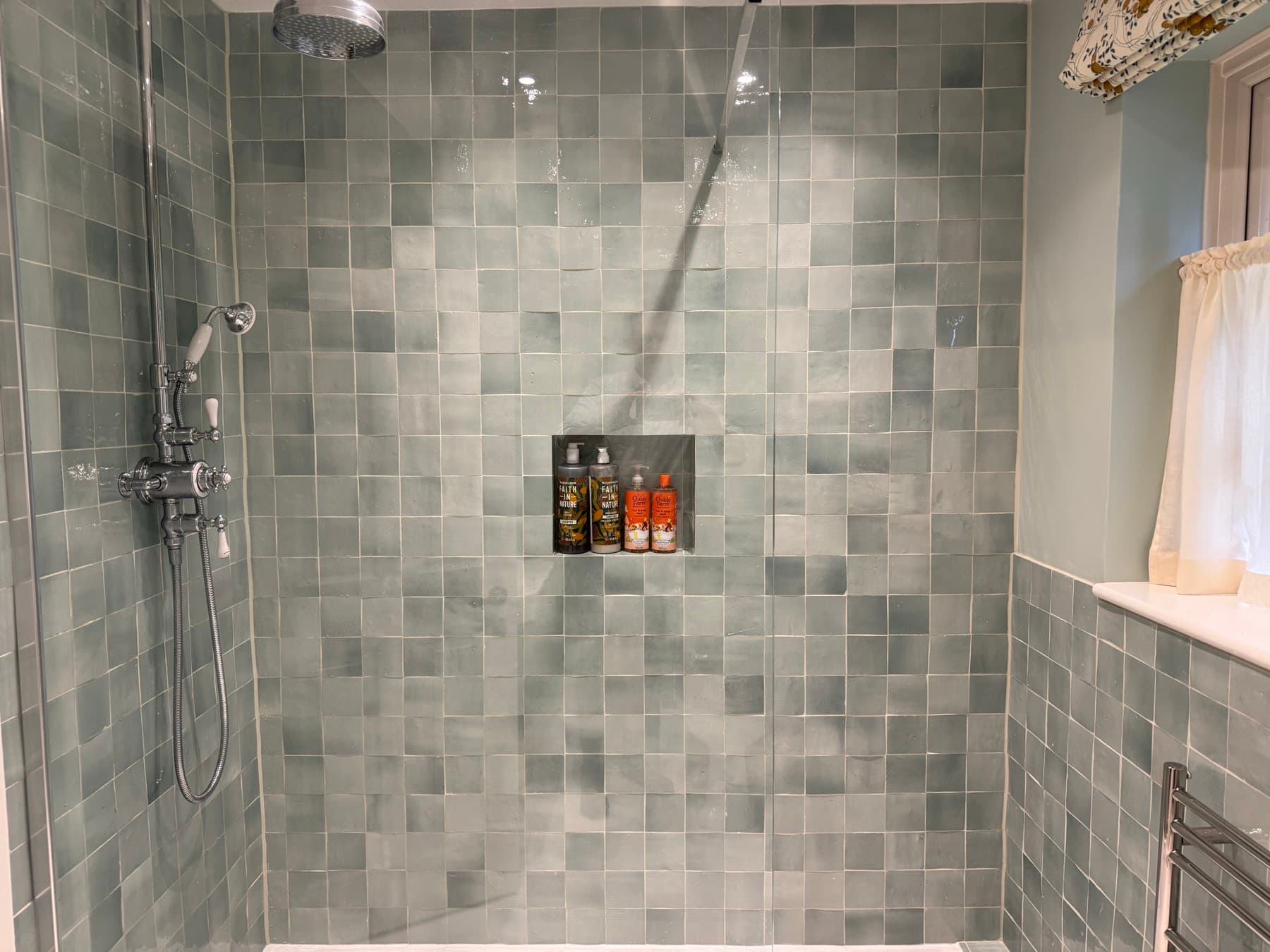 Walk-in shower with hand-made glazed tiles, a tiled niche and a traditional riser shower, refurbished by Rosebourne Plumbing