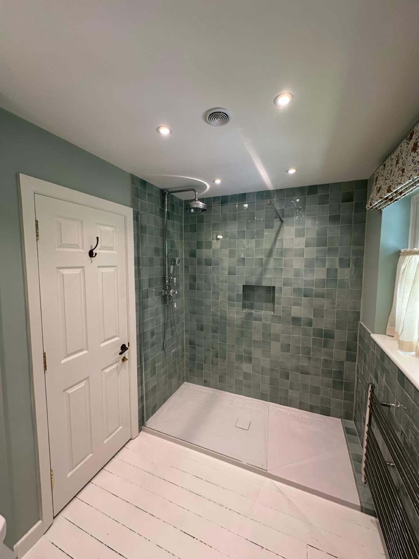 Walk-in shower with a ceiling extractor grille above it in a green-tiled shower room fitted by Rosebourne Plumbing