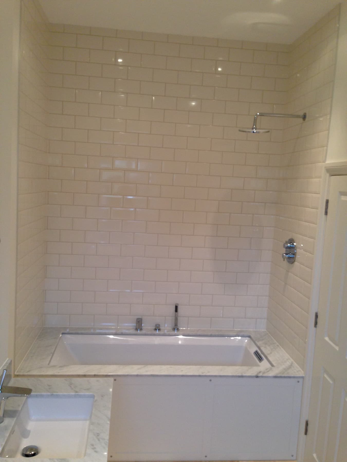 Reinstated bathroom with a shower over the bath, cream metro tiles and a marble-effect floor