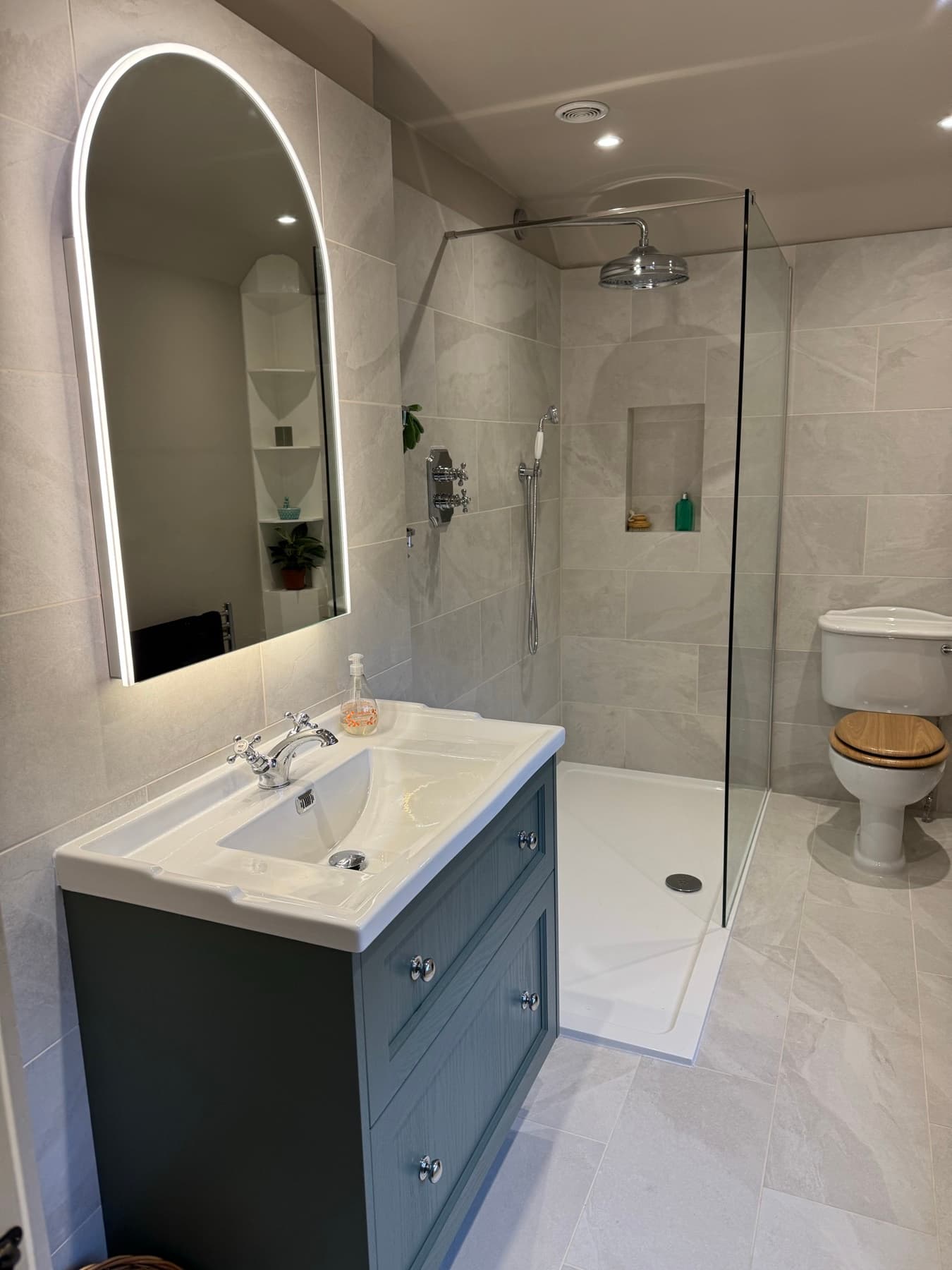 Finished shower room: walk-in shower, vanity basin and arched mirror