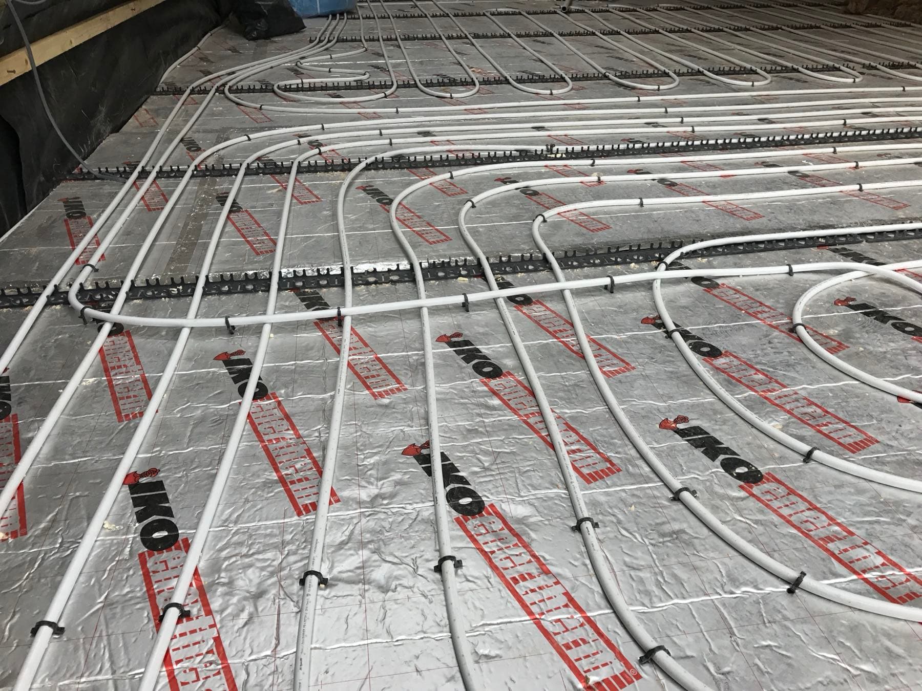 Wet underfloor heating pipe clipped in loops to foil-faced insulation before the screed goes down