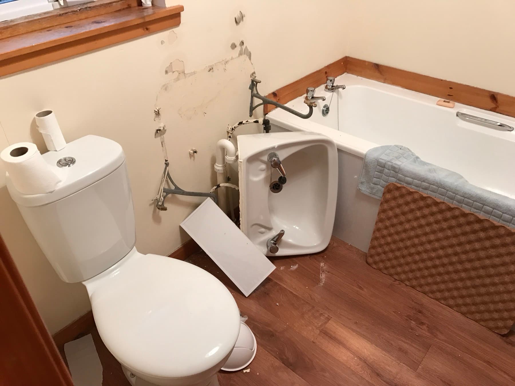 Basin torn away from a bathroom wall during an emergency call-out, pipework exposed