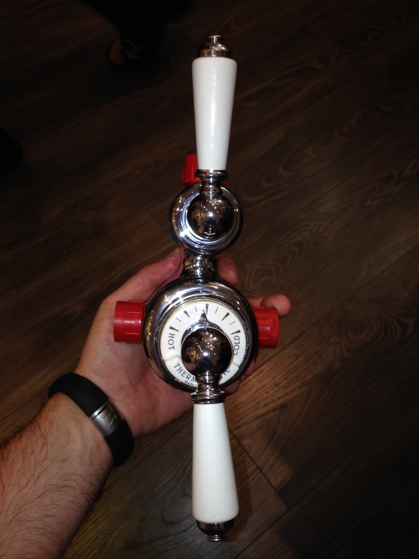 Traditional exposed thermostatic shower valve with white ceramic levers, held in a hand before fitting