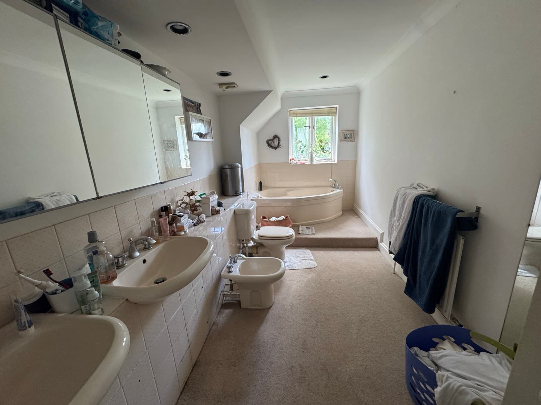 A tired bathroom before conversion, with the bath and old wall tiles still in place
