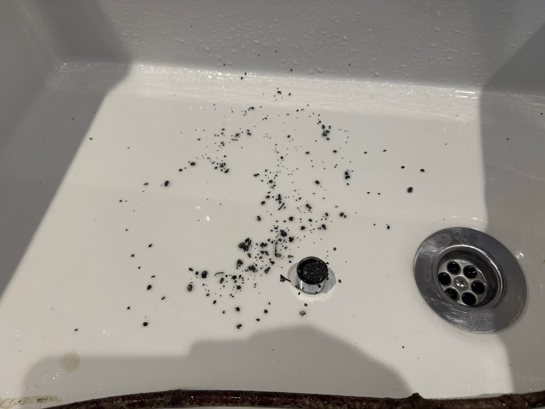 Black grit from the cold main flushed out onto a white bath