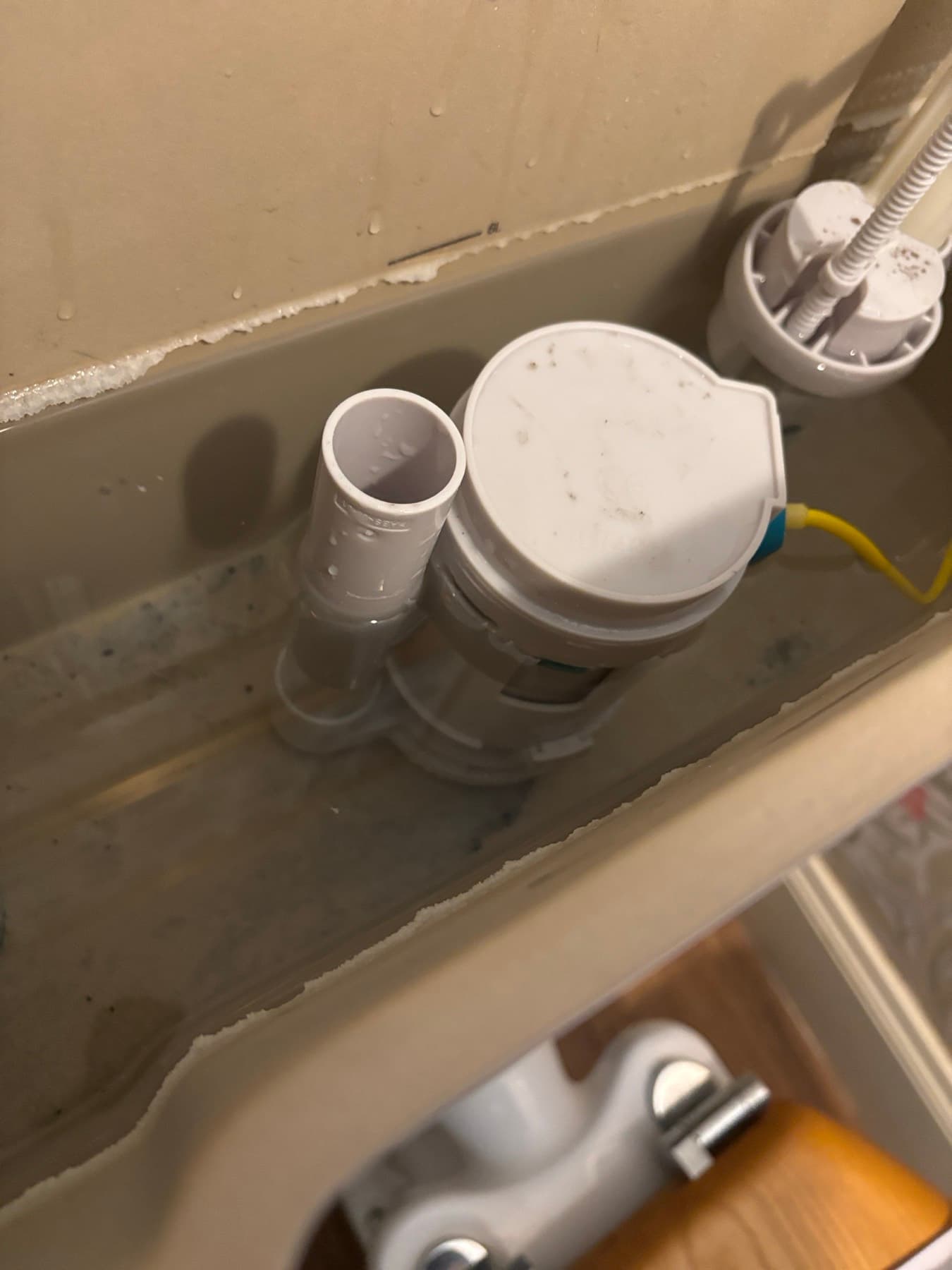 Inside a toilet cistern with the lid off: the fill valve on the right and the flush valve in the middle