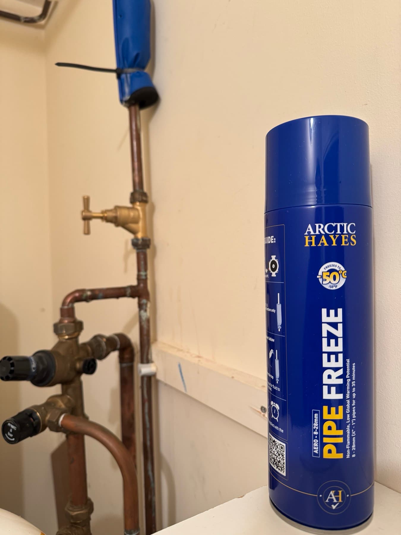 Can of Arctic Hayes pipe freeze spray beside an old brass stopcock in a cupboard